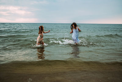 Siblings splashing and playing in the water at lake michigan