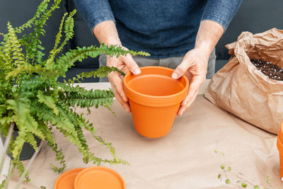 A man holds a terracotta clay pot in his hands. transplanting houseplants and landscaping at home.