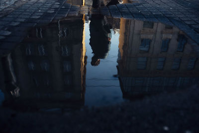 Reflection of woman walking on building in city