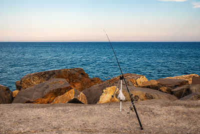 Fishing rod on the rocky quayside at sunset, liguria, italy
