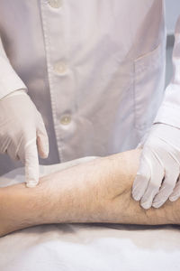 Midsection of doctor examining patient leg on hospital bed