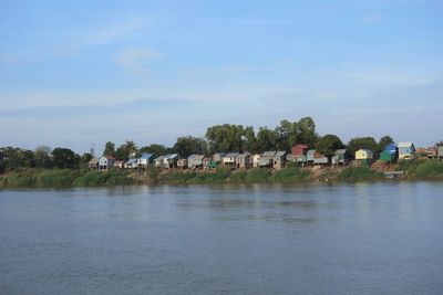 Houses by lake against sky