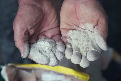 Close-up of cropped worker hands with cement