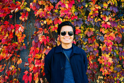 Portrait of man wearing sunglasses standing by autumn leaves