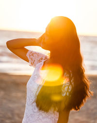 Close-up of woman standing on beach against sea during sunset