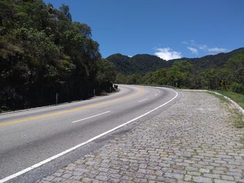 Empty road by mountain against sky
