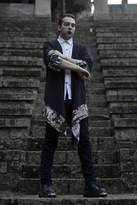 Portrait of young man standing against staircase