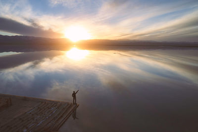 Silhouette mature man standing on pier over sea against sky during sunset