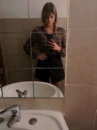 Portrait of young woman washing hands in bathroom