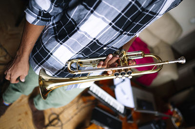 Young male musician holding trumpet at home