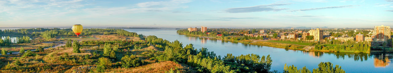 Panoramic view of trees and cityscape against sky