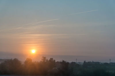 Scenic view of vapor trails in sky during sunset