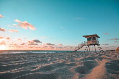 View of lifeguard hut on beach against sky during sunset