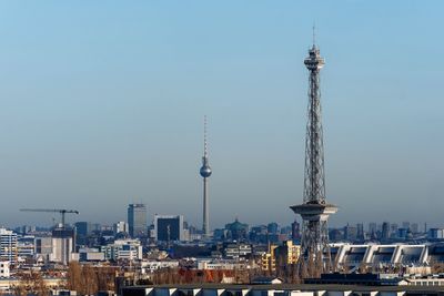 Communications tower in city against clear sky