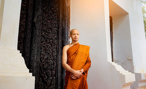 Monk wearing traditional clothing standing against closed doors