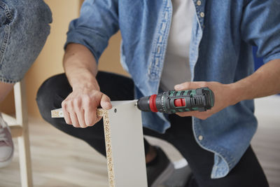 Midsection of man holding hands while sitting on floor