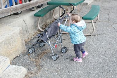 Baby girl with stroller walking on road