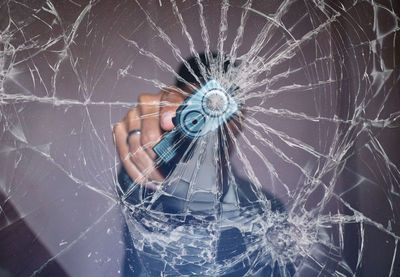 Close-up of man holding gun on broken glass