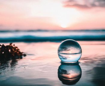 Close-up of water at beach against sky during sunset