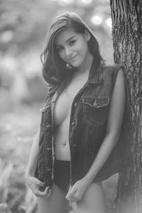 Portrait of seductive woman in jacket standing by tree