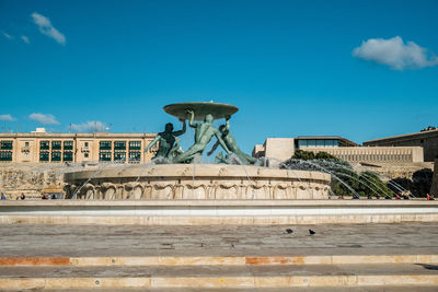 Statue of fountain in city against blue sky