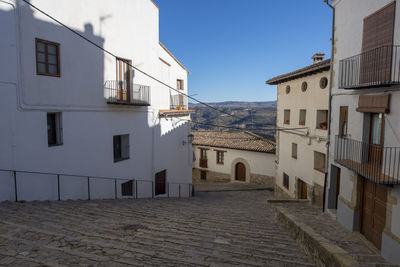 Alley amidst houses against sky in city