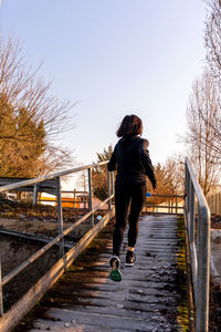 Young adult woman is running on a ship gangway in the morning - concept of health and wellness