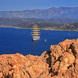 Boat sailing on sea against mountains