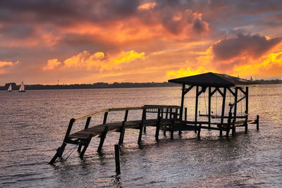 Pier over sea against sky during sunset