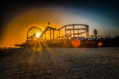 Amusement park ride against sky during sunset