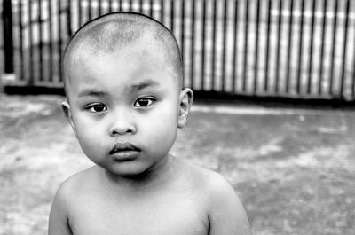 Close-up portrait of shirtless boy against railing