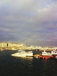 Boats in sea against cloudy sky