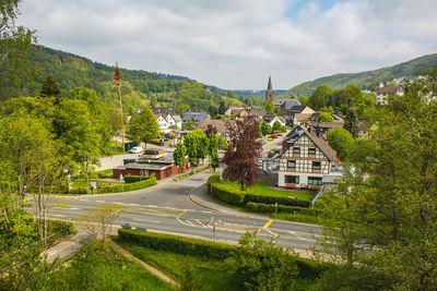 Road amidst trees and buildings against sky