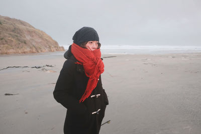 Man standing at beach against sky during winter
