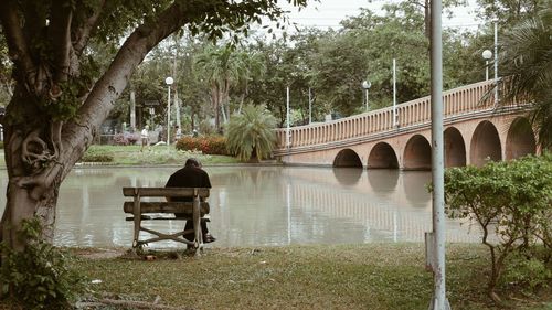 Scenic view of a man sitting on a park bench against lake