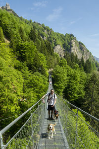 Rear view of woman walking on footbridge against mountain