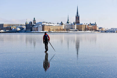 Reflection of person on river against buildings in city