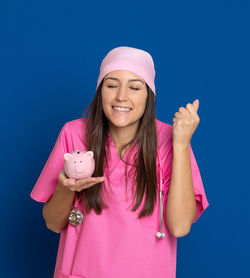 Portrait of a smiling young woman against blue background