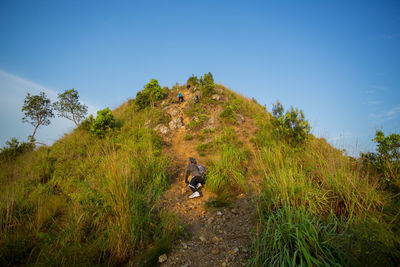 Man walking on mountain against clear blue sky