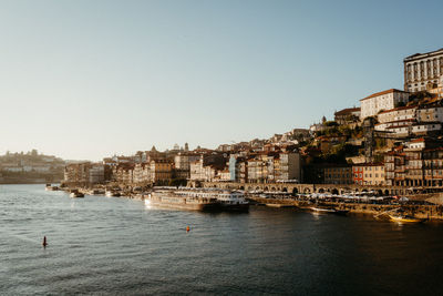 Buildings by sea against clear sky