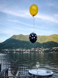 Balloons on lake against mountain range