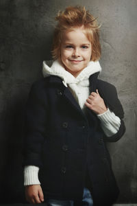 Portrait of teenage girl standing against wall