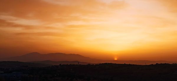Scenic view of silhouette mountains against orange sky