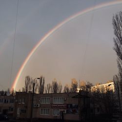 Rainbow over buildings in city against sky