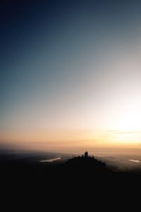 Silhouette people on land against clear sky during sunset