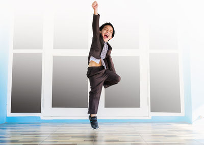 Full length portrait of boy shouting while standing on tiled floor