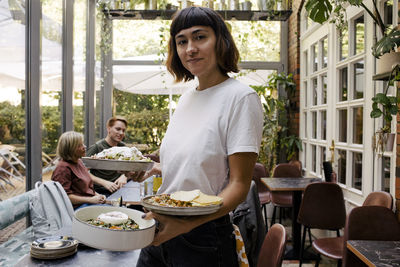 Portrait of owner serving food in plates