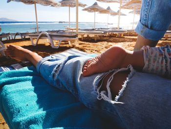 Low section of woman with baby boy relaxing at beach