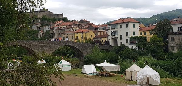 Houses by river amidst buildings in town against sky