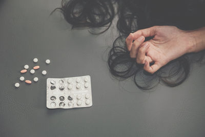 Cropped image of woman by pills over gray background